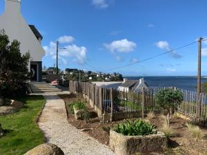 une clôture en face d'une maison avec vue sur l'océan dans l'établissement Perle des Abers Plage de Béniguet, à Saint-Pabu