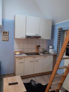 a kitchen with white cabinets and a wooden table at Münsterland Cottage in Lengerich