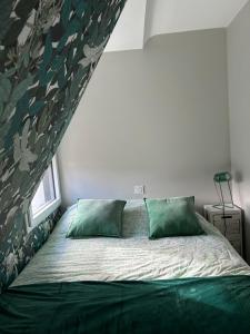 une chambre avec un lit avec deux oreillers verts dans l'établissement Perle des Abers Plage de Béniguet, à Saint-Pabu