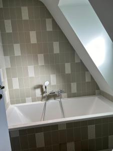 La salle de bains est pourvue d'une baignoire et de carrelage. dans l'établissement Perle des Abers Plage de Béniguet, à Saint-Pabu