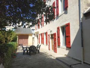 un tavolo e delle sedie davanti a un edificio con finestre rosse di L'Arénoulat ad Aspet Altre 4 foto