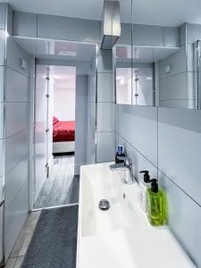 a white bathroom with a sink and a mirror at Ensuite Room with Jacuzzi in London