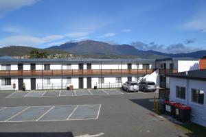 a parking lot in front of a building with mountains in the background at Hobart Tower Motel in Hobart