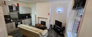uma sala de estar com um sofá e uma televisão numa cozinha em The Luxe - Entire House em Huddersfield