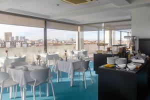 a restaurant with white tables and chairs and windows at Hotel Torre Mar in Póvoa de Varzim