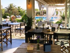 restauracja ze stołami i krzesłami oraz basenem w obiekcie Le Lanterne Resort w mieście Pantelleria