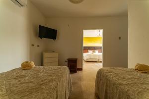 Habitación con 2 camas, TV y 1 dormitorio. en Hotel Boutique Noelani en Zorritos
