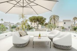 dos sillas blancas y una mesa y una sombrilla en Modern 4 Beds Luxe Villa 550m to Las Cañas Beach!, en Marbella