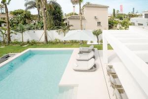 una piscina con 2 sillas y una sombrilla en Modern 4 Beds Luxe Villa 550m to Las Cañas Beach!, en Marbella