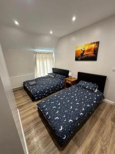 a bedroom with two beds and a table in it at Spacious and homely House in Nottingham