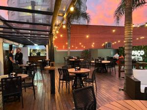 a restaurant with tables and chairs on a deck at Hotel Guest in Venâncio Aires