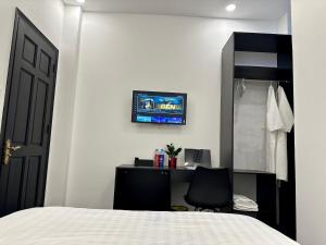 een slaapkamer met een bed, een bureau en een televisie bij Victoria Hotel in Ho Chi Minh-stad