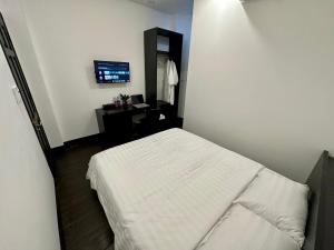 een slaapkamer met een wit bed en een bureau bij Victoria Hotel in Ho Chi Minh-stad