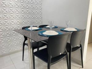 una mesa negra con cuatro sillas y copas de vino. en Apartamento 208 - Antares - Maceió, en Maceió