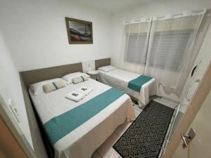 a small room with two beds and a window at Apto 2D Centro in Santa Cruz do Sul