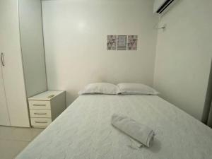 Un dormitorio blanco con una cama con una toalla. en Apartamento 208 - Antares - Maceió, en Maceió