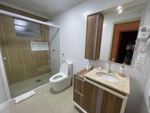 a bathroom with a toilet and a sink and a mirror at Apto 2D Centro in Santa Cruz do Sul