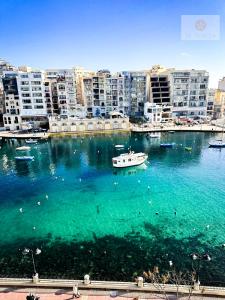 a boat in a large body of water with buildings at Ta' Tereża Seafront Apartments in St. Julianʼs