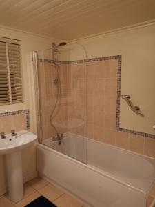uma casa de banho com um chuveiro, uma banheira e um lavatório. em The Nook @ Rowan Tree Cottage em Ballymoney