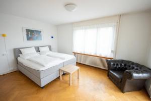 a bedroom with a bed and a leather chair at Luegete 28, Witikon Apartments in Zürich