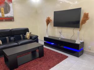 a living room with a black couch and a flat screen tv at Charmante petite villa aux Mamelles in Ouakam