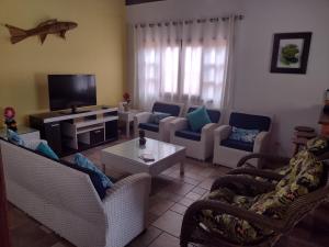Una sala de estar con sofás y un televisor de pantalla plana. en Casa dos Prados, en Peruíbe