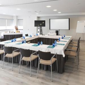 uma sala de conferências com mesas e cadeiras e um ecrã de projecção em Hotel & Spa Real Ciudad De Zaragoza em Zaragoza