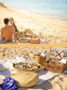 um homem e uma mulher sentados na praia com uma mesa de comida em Appartement Clube Praia Da Rocha III em Portimão