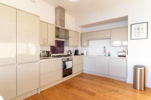a kitchen with white cabinets and a hardwood floor at Rock Pool in Mortehoe