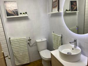 ein Badezimmer mit einem WC, einem Waschbecken und einem Spiegel in der Unterkunft Apartamento primera línea de playa en Somo in Somo