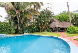 a large blue swimming pool in a resort with palm trees at Tranquilidad cerca de la playa in Bucerías