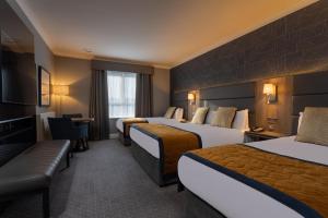 ゴールウェイにあるクリボーンホテルのベッド3台とソファが備わるホテルルームです。