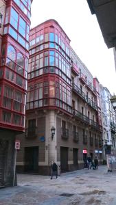 un edificio rojo alto con gente parada frente a él en Casual Fuentes, en Bilbao