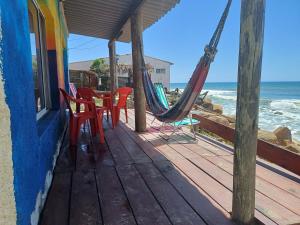 een veranda met stoelen en een hangmat en de oceaan bij Amanecer en aguas dulces in Aguas Dulces