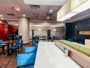 un comedor con sillas azules, mesas y sillas en Courtyard by Marriott Alexandria Pentagon South, en Alexandria