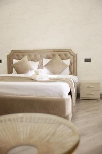 Royal Renaissance Hotel في يريفان: غرفة نوم بسرير كبير عليها شراشف ووسائد بيضاء
