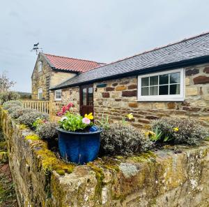 a stone retaining wall with flowers in front of a house at Twattleton Cottage Kilburn Yorkshire - Beautiful views in York