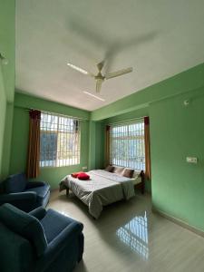 a bedroom with a bed and a couch and two windows at Sana Riverside in Madikeri