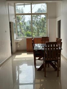 comedor con mesa, sillas y ventana en Sana Riverside, en Madikeri