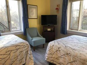 1 dormitorio con 2 camas, silla y TV en Braeside Country Inn, en Pictou