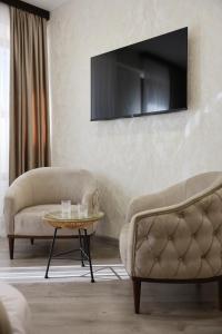 ein Wohnzimmer mit 2 Stühlen und einem TV an der Wand in der Unterkunft Royal Renaissance hotel in Yerevan