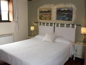 a white bed in a bedroom with two lamps at Casa Rural Ozollo in Gautegiz Arteaga