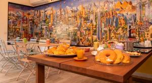 a table with bread and donuts on it with a mural at Wanderlust Guesthouse in Gaeta