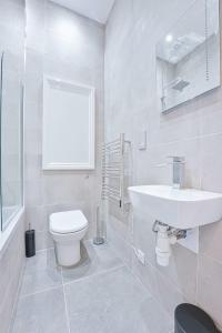 La salle de bains blanche est pourvue de toilettes et d'un lavabo. dans l'établissement Modern 2 Bedroom Apartment in Central Cheltenham, à Cheltenham