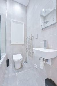 a white bathroom with a toilet and a sink at Stylish 2 Bedroom Apartment in Central Cheltenham in Cheltenham