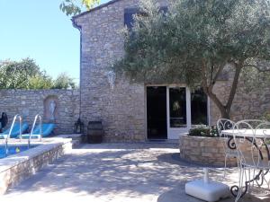 Casa de piedra con piscina, mesa y sillas en Maison de charme, en Aix-en-Provence