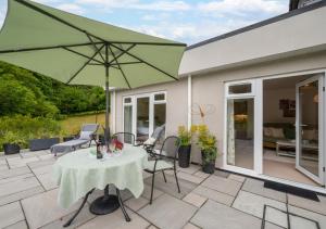 a patio with a table and a green umbrella at Nyth Bryn Haul in Llanidloes