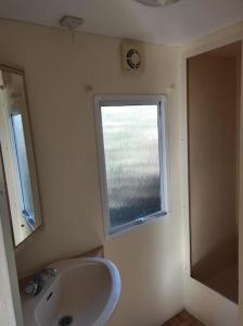 a bathroom with a sink and a window at Mobil-home dans un beau cadre à 15 km des plages. in Lunel
