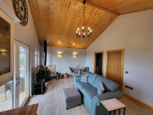 a living room with a blue couch and a wooden ceiling at White O'Morn Cabin in Newry