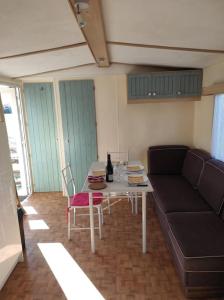 a living room with a couch and a table at Mobil-home dans un beau cadre à 15 km des plages. in Lunel